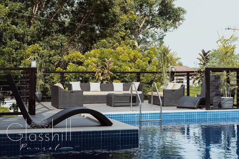 Poolside chaise loungers, blue mosaic pool, and hillside backdrop